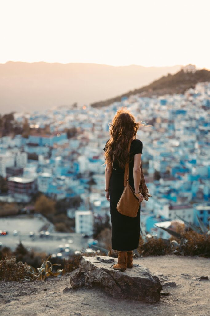 Woman overlooking the blue city of Chefchaouen from a panoramic viewpoint in Morocco.